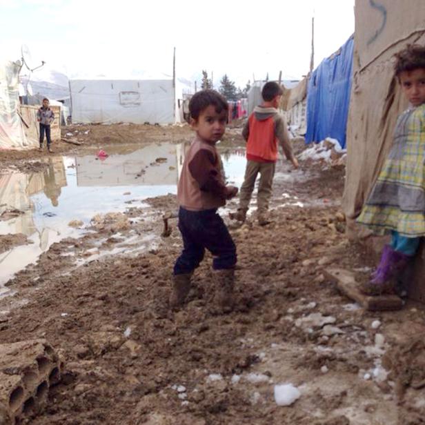 Kinder spielen in einem schlammigen Flüchtlingslager.