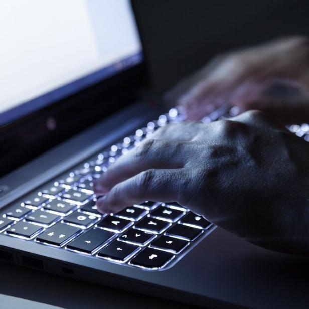Eine Person tippt auf einem Laptop mit beleuchteter Tastatur.