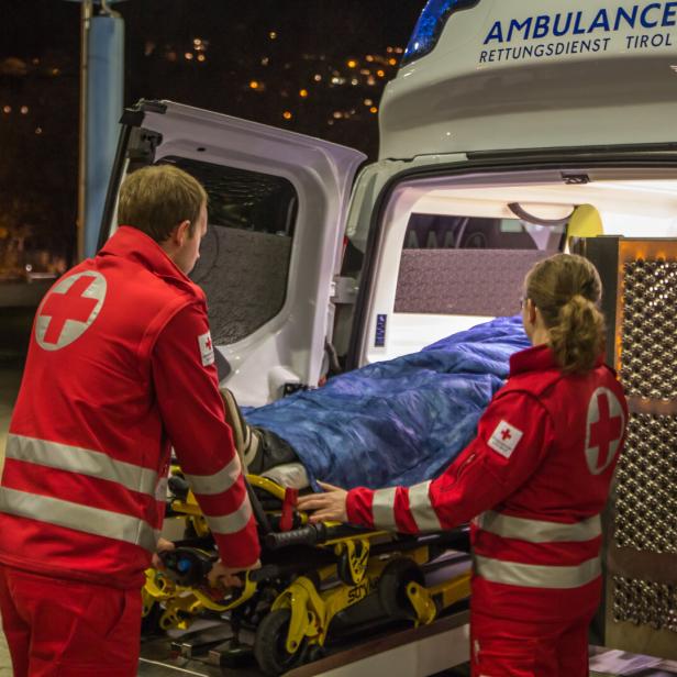 Zwei Sanitäter schieben eine Trage in einen Rettungswagen des Rettungsdienstes Tirol.