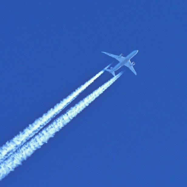 Flugzeug mit Kondensstreifen am Himmel.