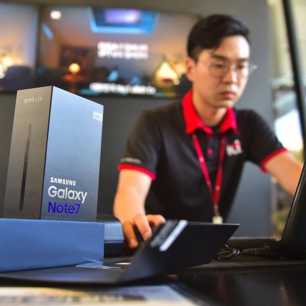 Ein Mann arbeitet an einem Laptop neben einer Verpackung für ein Samsung Galaxy Note 7.