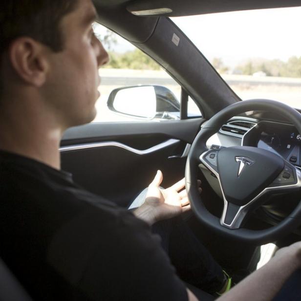 Ein Mann fährt ein Tesla-Auto mit den Händen nicht am Lenkrad.