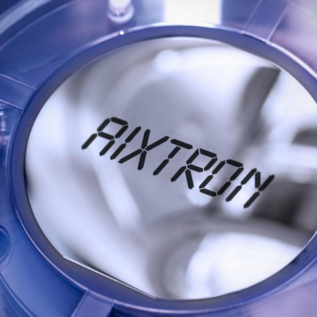 Das Logo von AIXTRON in einem blauen, transparenten Gehäuse.