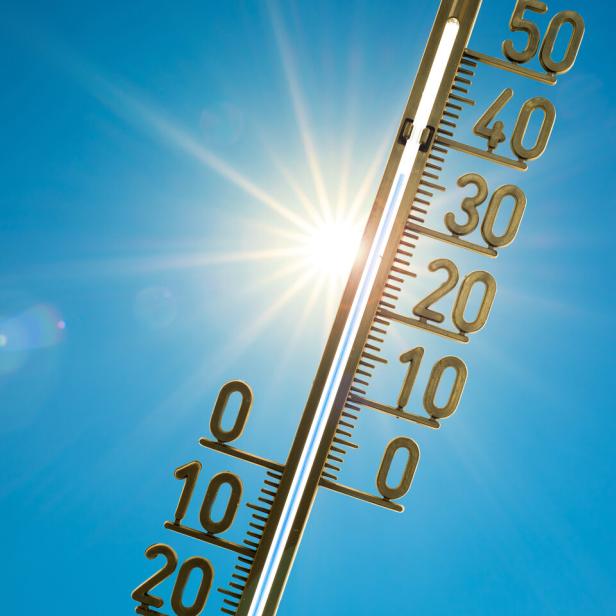 Ein Thermometer wird in den blauen Himmel gehalten.