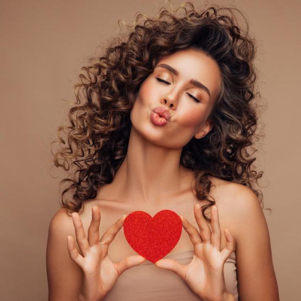 Young beautiful woman holding artificial heart