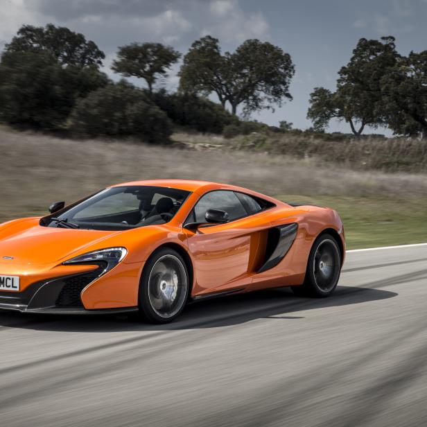 Ein orangefarbener McLaren Sportwagen fährt auf einer Landstraße.