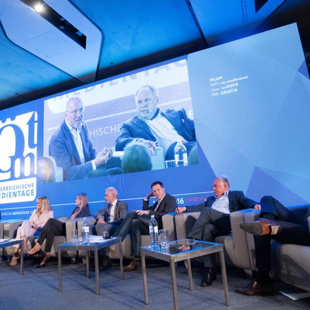Eine Podiumsdiskussion bei den Österreichischen Medientagen vor einer großen Leinwand.