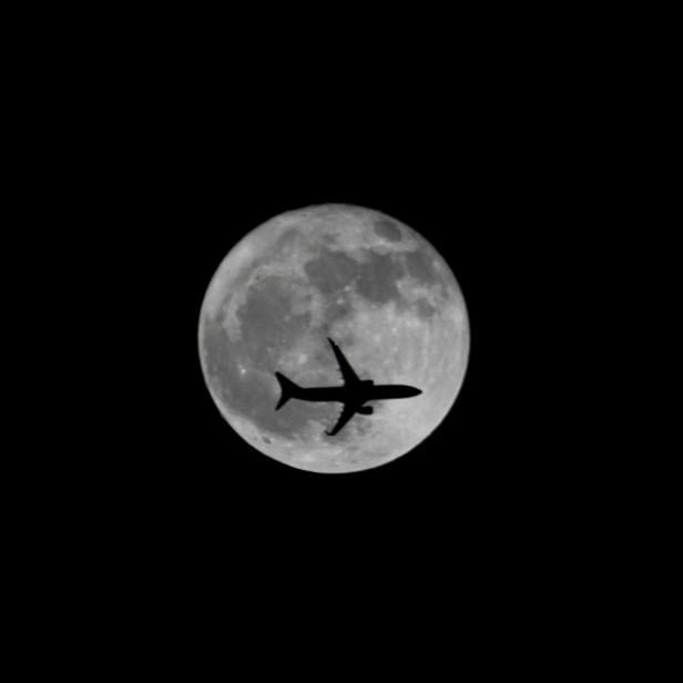 FILE PHOTO: Passenger plane passes the moon as it comes into land at the international airport in Chennai