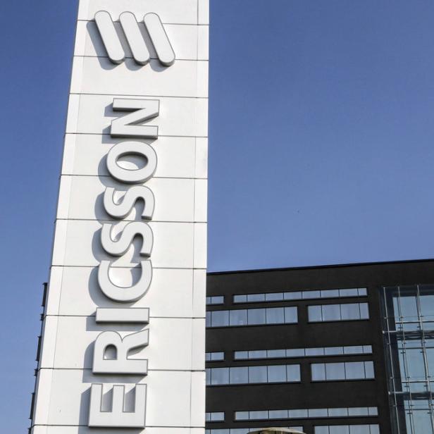 Das Ericsson-Logo vor einem Bürogebäude unter blauem Himmel.