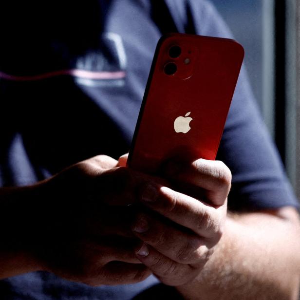 Eine Person hält ein rotes iPhone in der Hand.