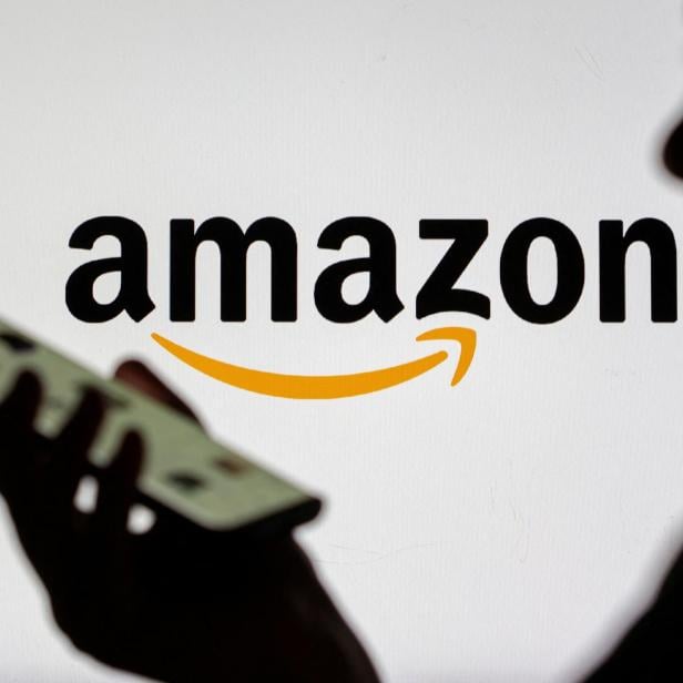 FILE PHOTO: Woman with smartphone is seen in front of displayed Amazon logo in this illustration taken