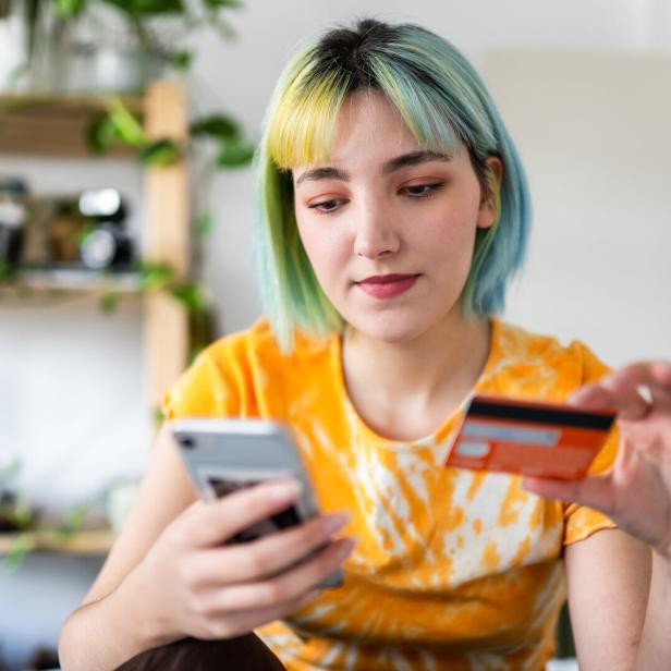 Symbolbild: Eine Frau mit Kreditkarte und Smartphone.