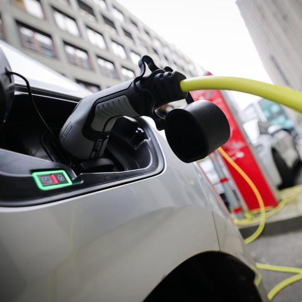 Ein Elektroauto wird an einer Ladestation mit einem gelben Kabel aufgeladen.