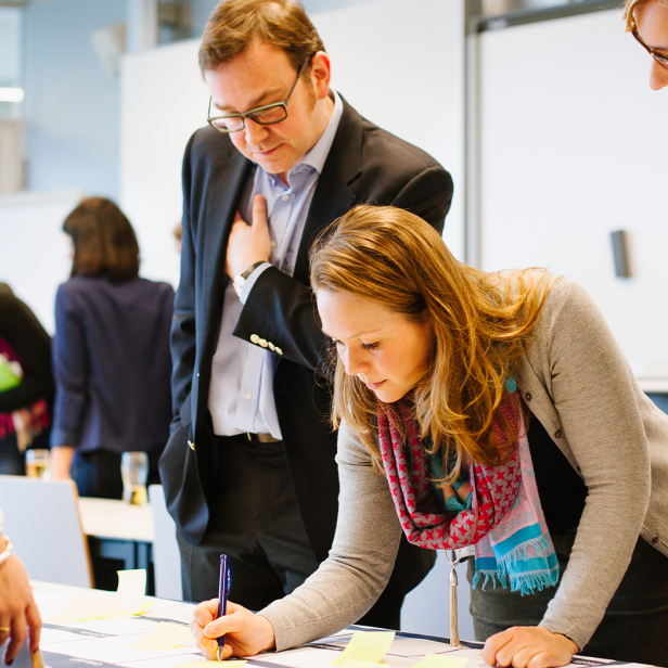 Eine Gruppe von Menschen arbeitet gemeinsam an einem Tisch mit Haftnotizen.