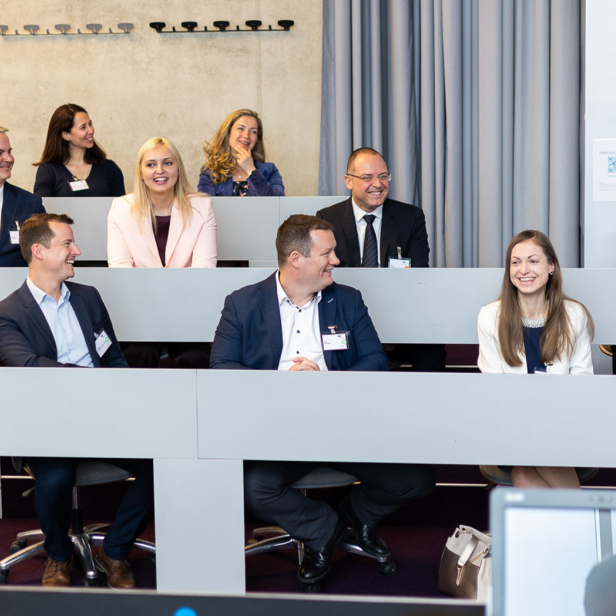 Zuschauer sitzen in einem Auditorium und lächeln.