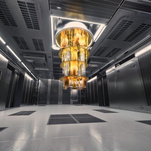Ein großer, goldfarbener Quantencomputer hängt zentral in einem modernen, technisch ausgestatteten Serverraum von der Decke.