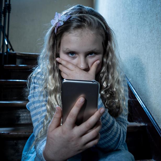 Sad depressed girl Bullied by text message humiliated online social media by classmates. Sad depressed young girl victim of cyberbullying by mobile phone sitting on stairs feeling lonely hopeless.