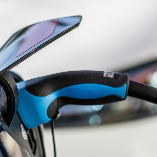 Ein blauer Ladestecker ist mit einem Elektroauto verbunden.