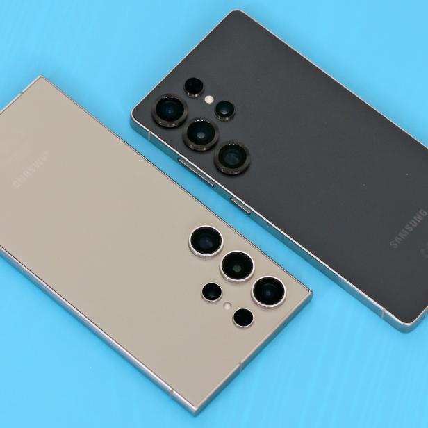 Zwei Samsung Galaxy Smartphones, ein S24U und ein S25U, liegen auf einem blauen Hintergrund.