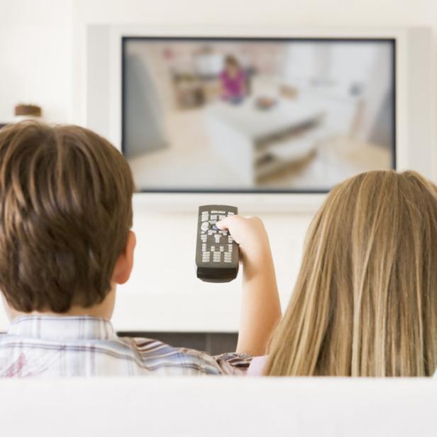 Eine Familie sitzt vor dem Fernseher und schaut fern.