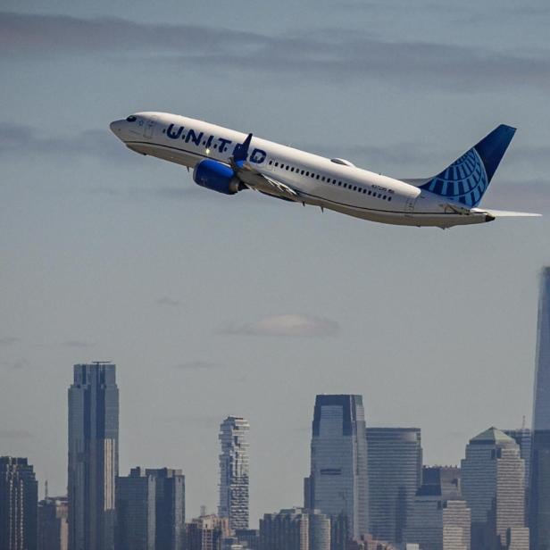 ein United-Airlines Flugzeug im Steigflug vor einer Hochhaus-Skyline