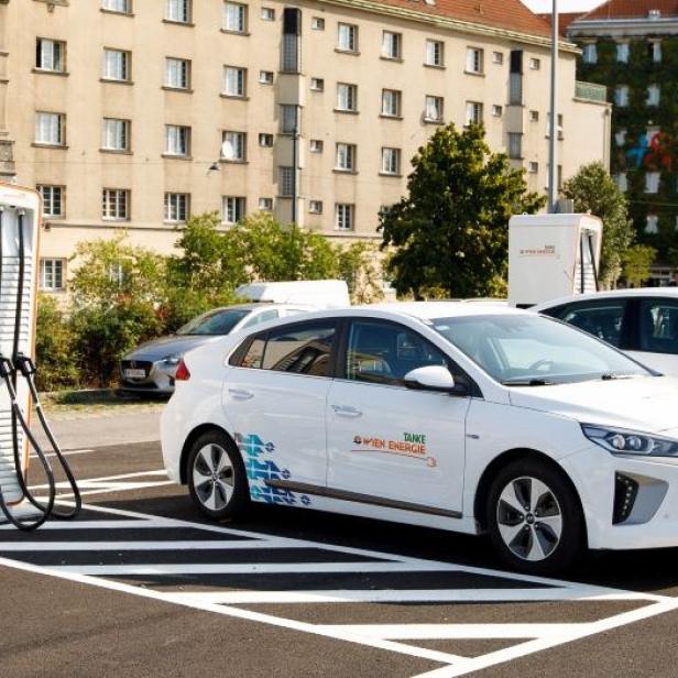 Ein E-Auto auf einem Parkplatz in Wien neben einer E-Ladestation von Wien Energie. 