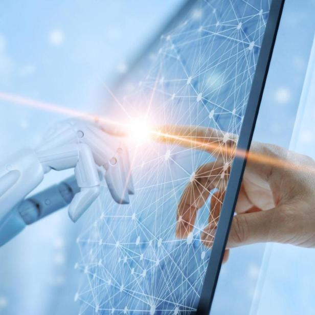 Eine Roboterhand berührt mit einem Finger einen menschlichen Finger.