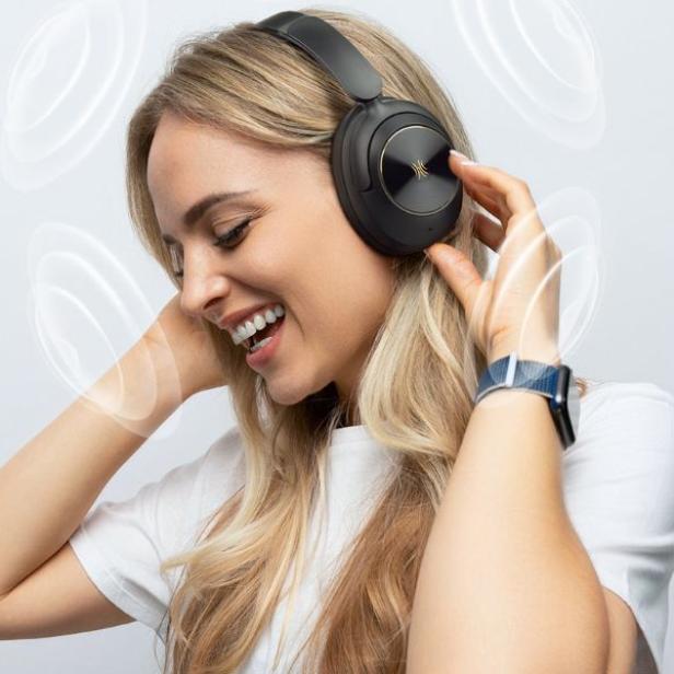 Eine Frau hat Kopfhörer auf und genießt es Musik zu hören.