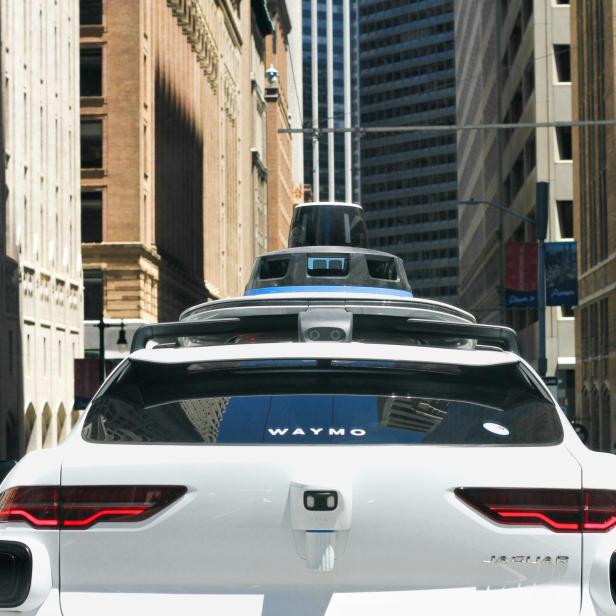 Ein weißer Waymo Jaguar fährt durch eine Stadt.