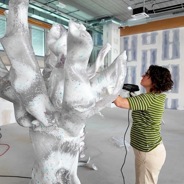 Eine Frau arbeitet an einem Plastikbaum.