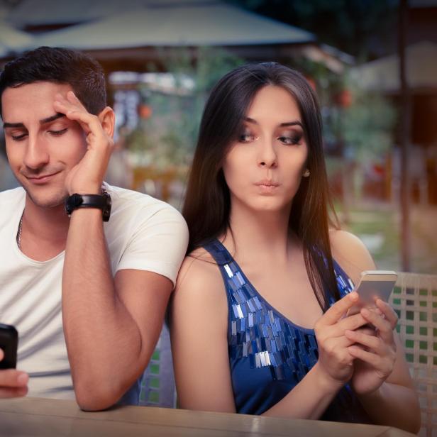 Symbolbild: Eine Frau liest am Smartphones eines Mannes Nachrichten mit