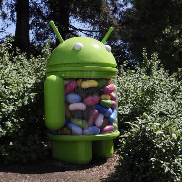 Eine grüne Android-Statue, gefüllt mit bunten Süßigkeiten, steht im Freien.