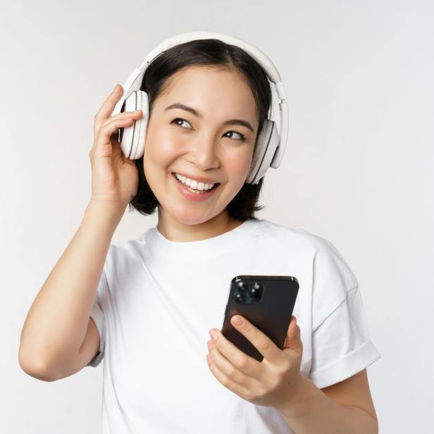 Frau mit Kopfhörern und Handy.