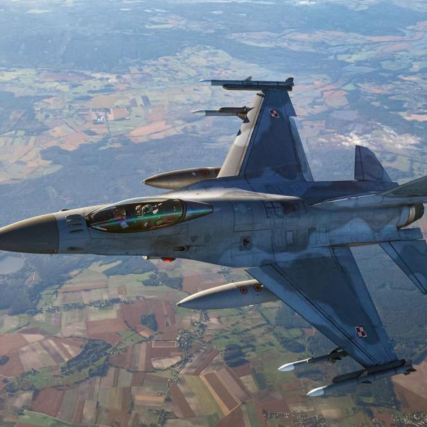 Ein polnisches Kampfflugzeug F-16 im Flug über Felder.