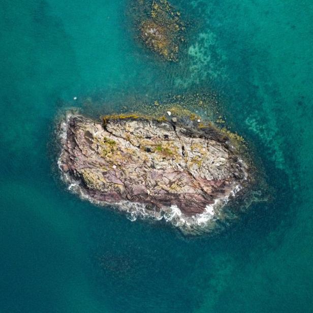 Insel und Unterwasserberge in türkisem Wasser, Vogelperspektive