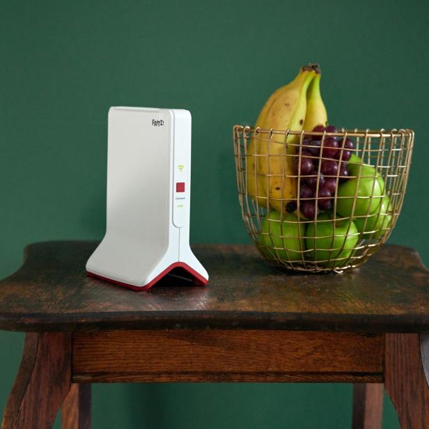 Ein Fritz!Box Router und ein Korb mit Obst stehen auf einem Tisch.