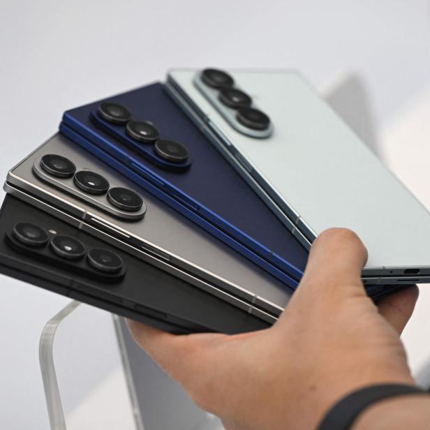 Eine Hand hält vier Samsung Galaxy Z Fold Smartphones in verschiedenen Farben.