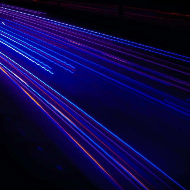 Lichtspuren von Autos auf einer dunklen Autobahn bei Nacht.