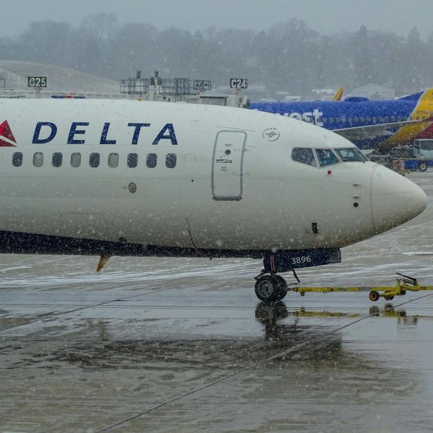 Ein Symbolbild für ein Flugzeug von Delta, das am Flughafen im Regen steht.
