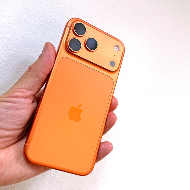 Ein orangefarbenes iPhone 17 Pro Max wird in der Hand gehalten.