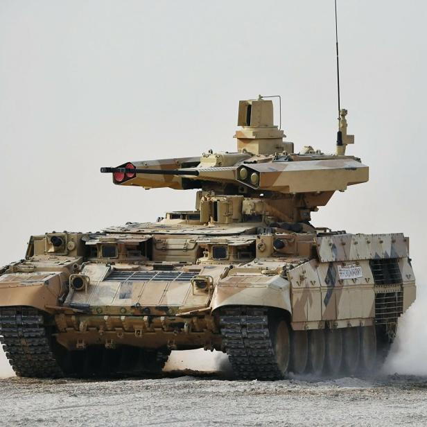 Ein BMPT Terminator-1 Kampfpanzer fährt durch staubiges Gelände.