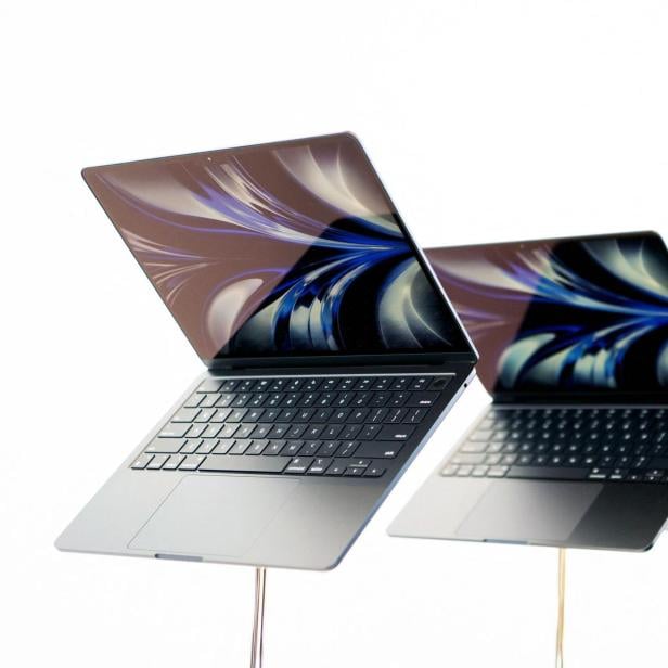 Mehrere geöffnete MacBooks stehen in einer Reihe vor einem weißen Hintergrund.