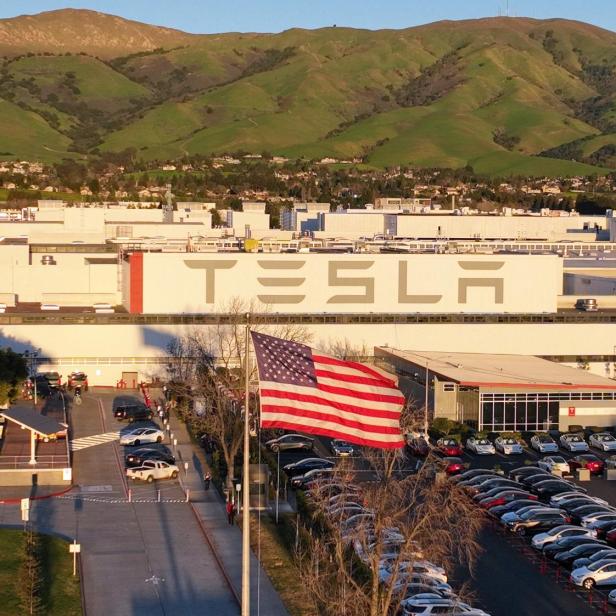 Vor einer Tesla-Fabrik wehen die amerikanische Flagge und die Flagge Kaliforniens.