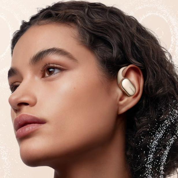 Eine Frau trägt goldfarbene Xiaomi Open Wear Stereo Pro Ohrhörer.