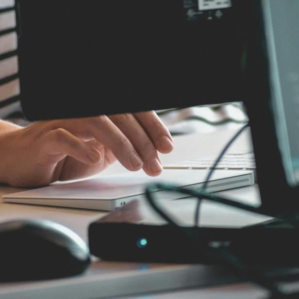 Eine Person tippt auf einer Tastatur und benutzt eine Maus.