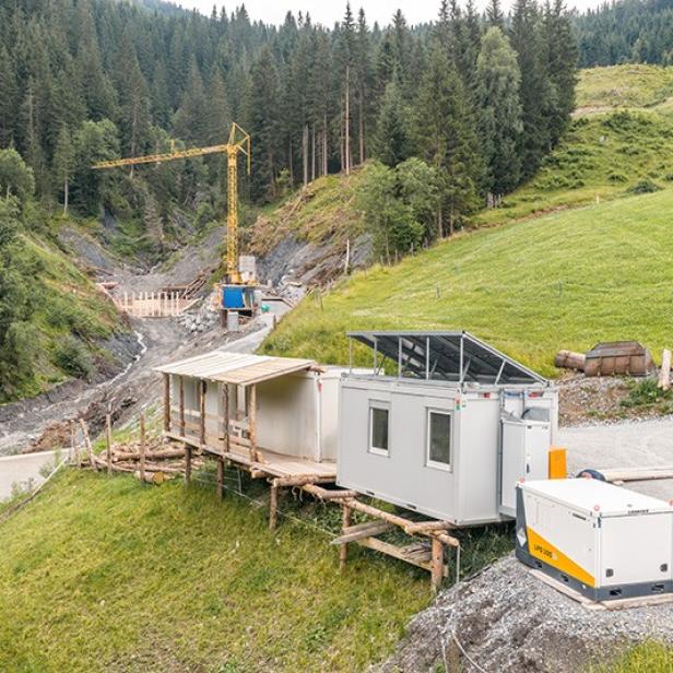 Ein Liebherr-Akku mit 94 kWh Kapazität versorgt eine Baustelle im Salzburger Gebirge, um Schutzmaßnahmen gegen Steinschlag zu ermöglichen.