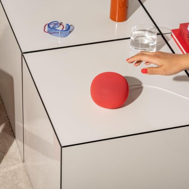 Neuer Google-Lautsprecher in Rot mit Hand, die in die Richtung greift