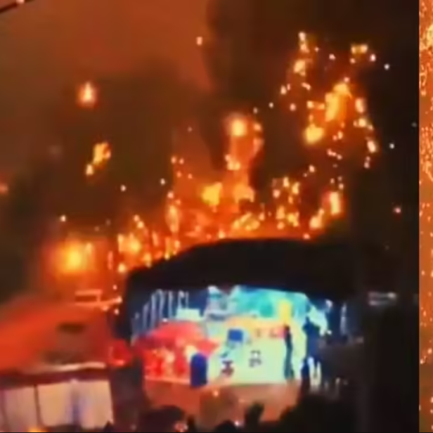 Brennende Feuerbälle und Funkenregen fallen bei einer nächtlichen Drohnenshow herab.