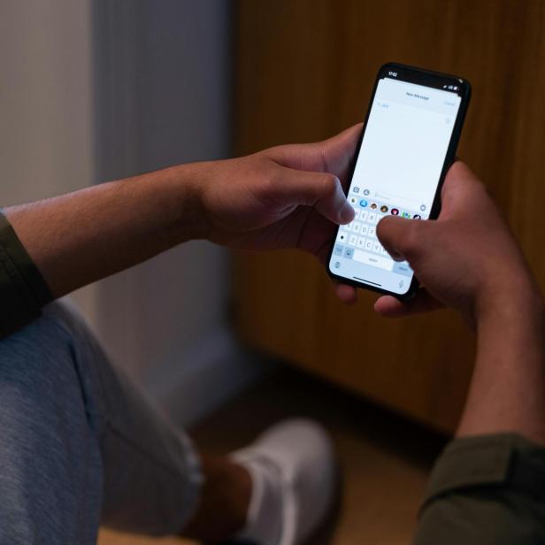 Ein Mann hält ein Handy in der Hand, eine Messenger-App ist geöffnet