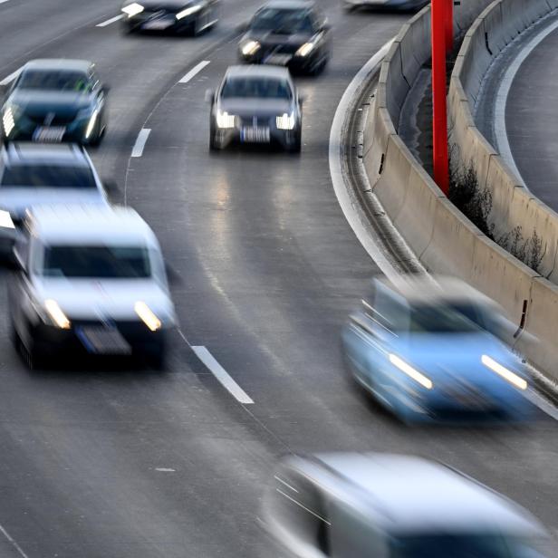 Autos fahren mit eingeschalteten Scheinwerfern auf einer Autobahn.